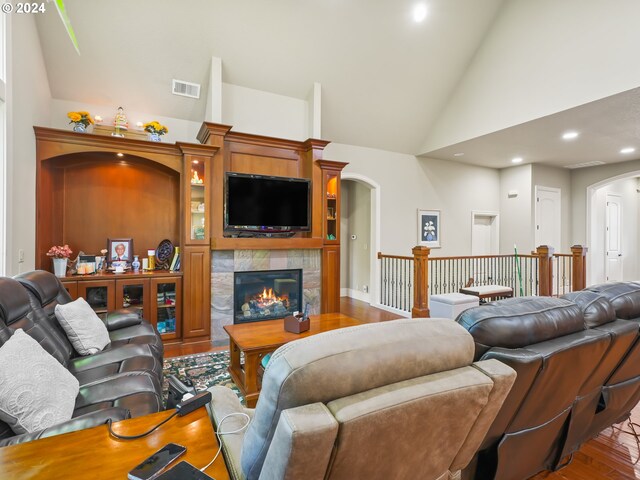 living room featuring high vaulted ceiling, a fireplace, and wood-type flooring