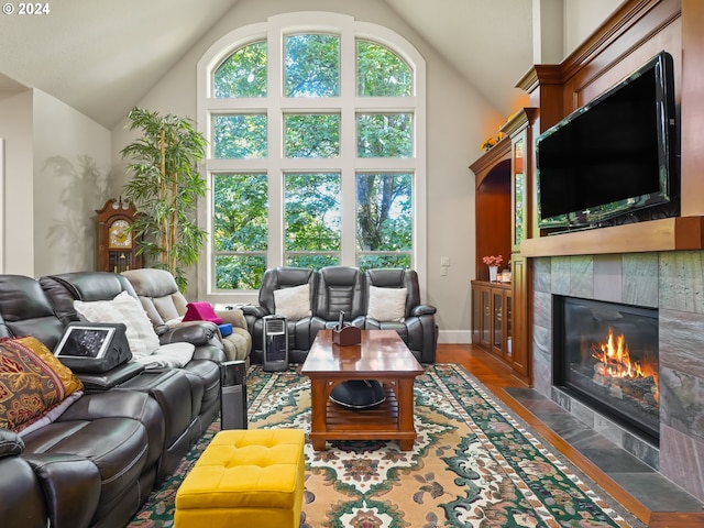 living room featuring dark hardwood / wood-style floors, high vaulted ceiling, and a tiled fireplace