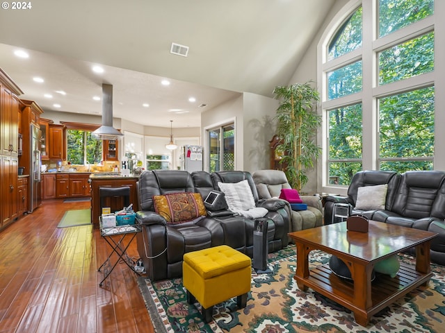 living room with plenty of natural light, high vaulted ceiling, and light hardwood / wood-style flooring