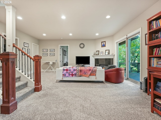 carpeted living room featuring decorative columns and a tiled fireplace