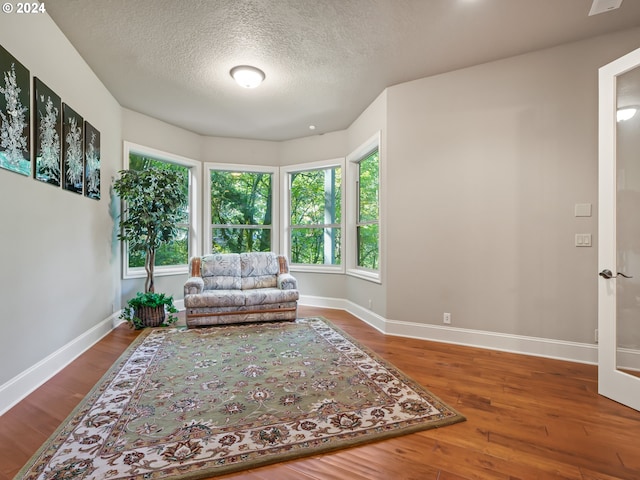 living area featuring wood-type flooring and a textured ceiling