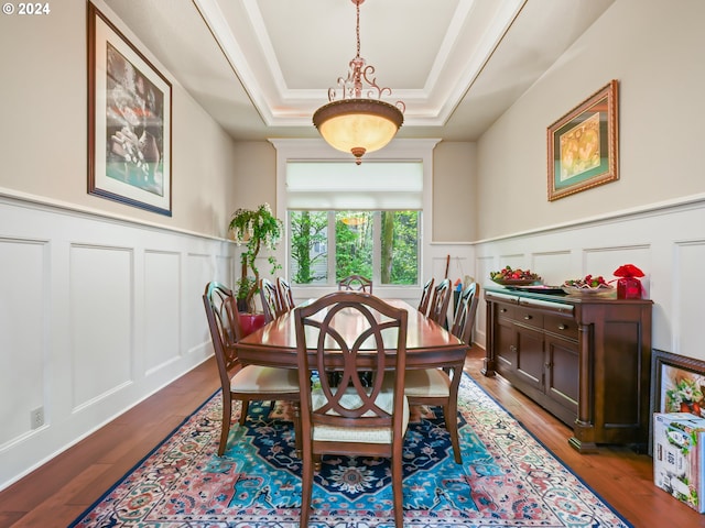 dining room with ornamental molding, light wood-type flooring, and a tray ceiling