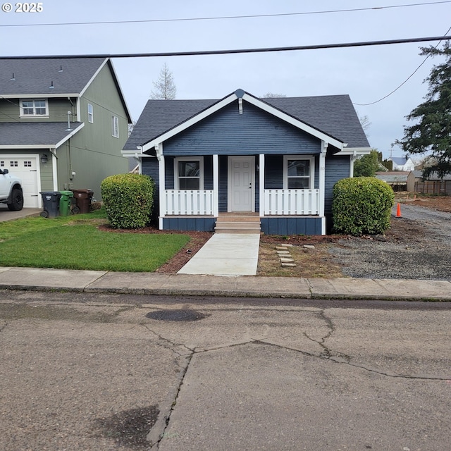 bungalow with a shingled roof, covered porch, and a front lawn