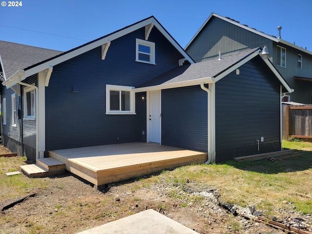 back of property with roof with shingles and a deck