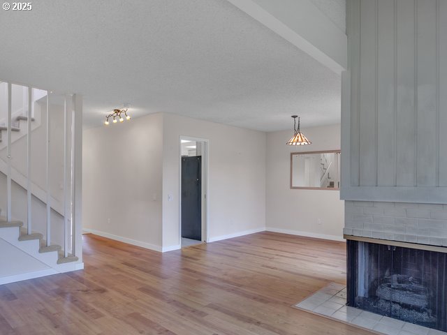 unfurnished living room with a fireplace, light hardwood / wood-style flooring, and a textured ceiling