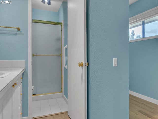 bathroom featuring hardwood / wood-style flooring, vanity, and a shower with door