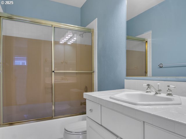 full bathroom with toilet, vanity, and bath / shower combo with glass door