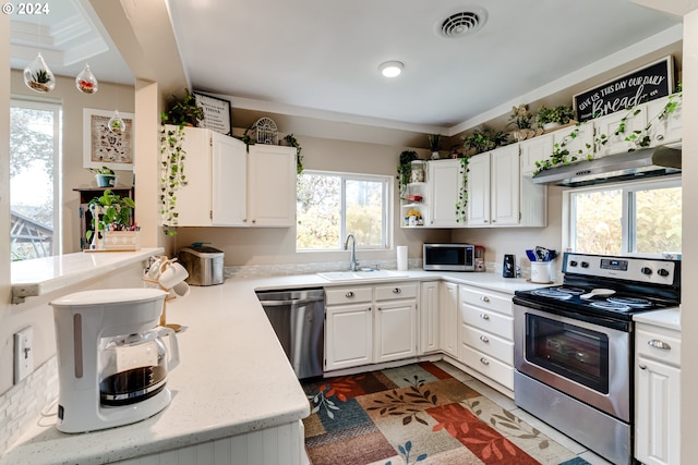 kitchen featuring white cabinets, appliances with stainless steel finishes, kitchen peninsula, and sink