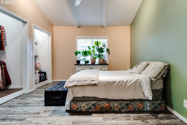 bedroom with vaulted ceiling with beams and light hardwood / wood-style flooring