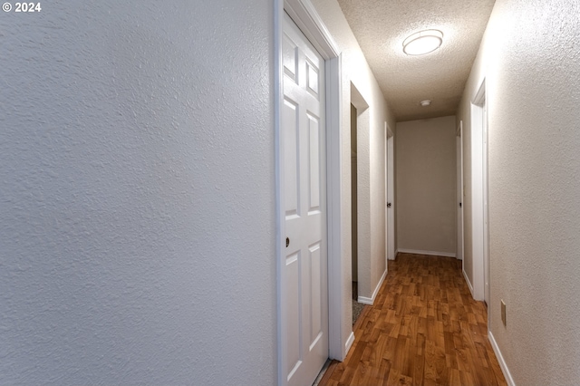 hallway with hardwood / wood-style floors and a textured ceiling