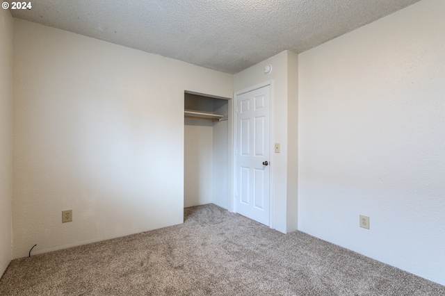 unfurnished bedroom with a closet, a textured ceiling, and carpet floors