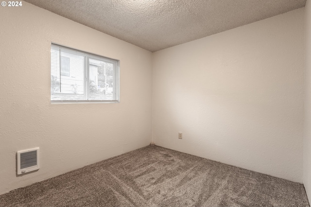 empty room featuring carpet, heating unit, and a textured ceiling