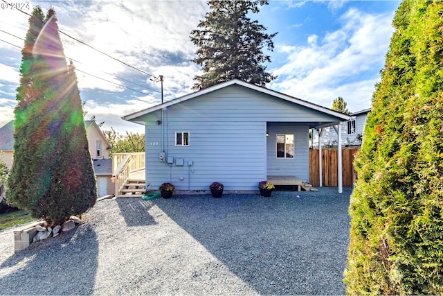 back of property featuring gravel driveway and fence