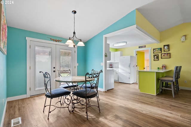 dining room featuring french doors, light hardwood / wood-style floors, and vaulted ceiling