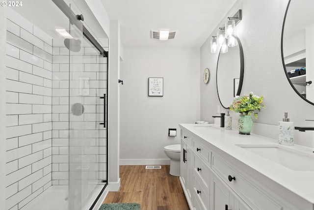 bathroom featuring vanity, toilet, a shower with shower door, and wood-type flooring