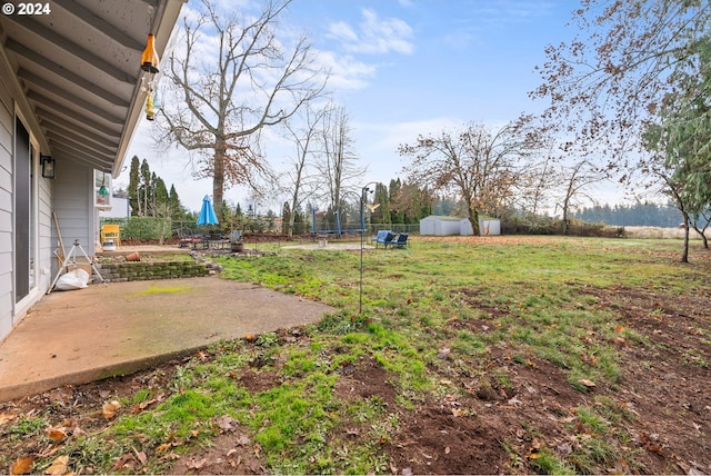 view of yard with a trampoline, a storage shed, and a patio area