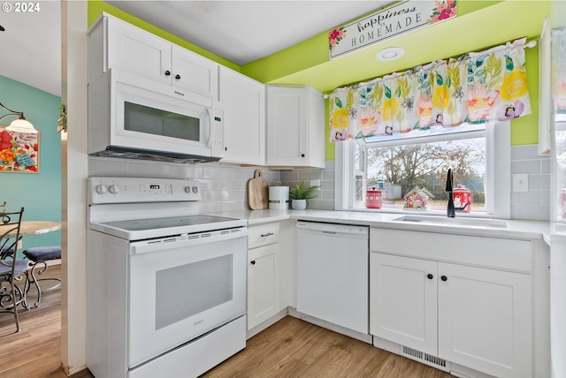 kitchen featuring decorative backsplash, white appliances, sink, light hardwood / wood-style floors, and white cabinetry