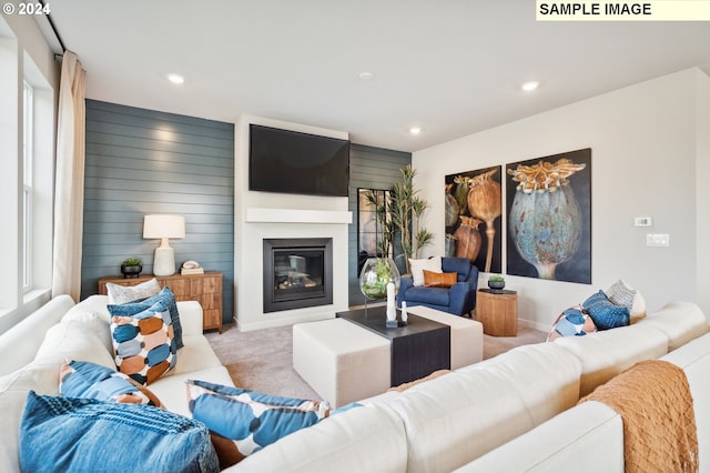 carpeted living room featuring a fireplace and wooden walls