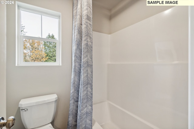 bathroom with a shower with shower curtain and toilet