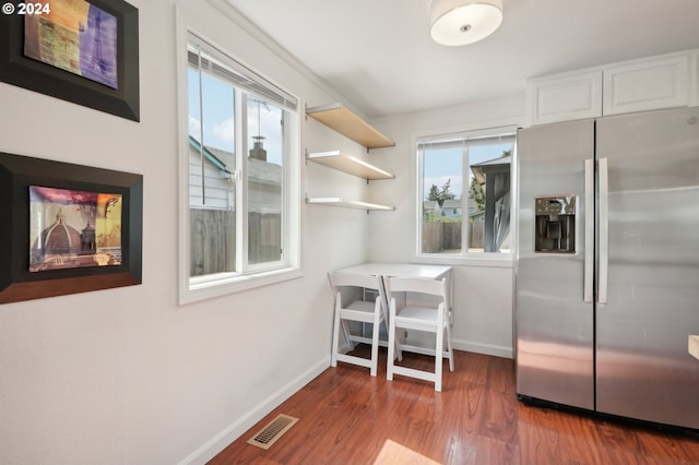 kitchen featuring stainless steel refrigerator with ice dispenser, plenty of natural light, dark hardwood / wood-style flooring, and white cabinetry