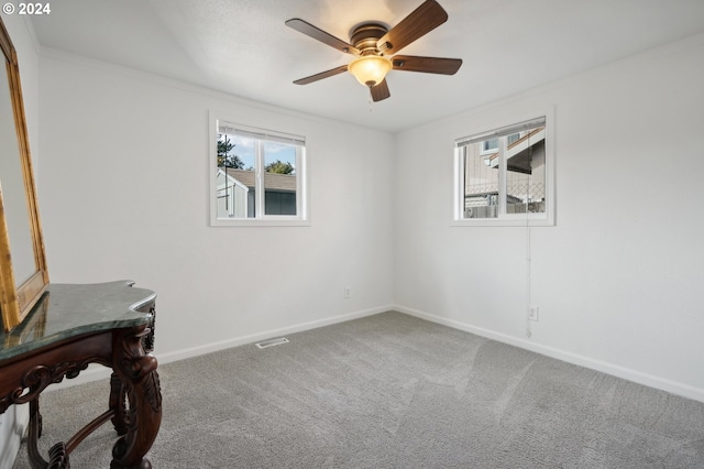 carpeted spare room featuring crown molding and ceiling fan