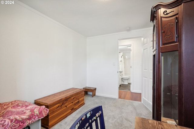 bedroom featuring ornamental molding, ensuite bath, and light carpet