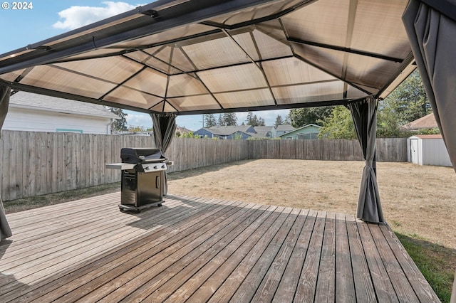 wooden terrace featuring a shed, a gazebo, and grilling area