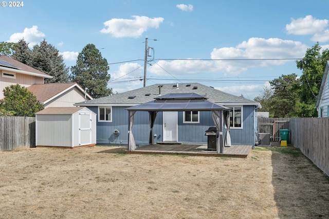 back of property with a deck, a lawn, and a shed