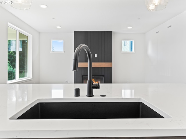 interior details with a large fireplace, sink, and light stone counters