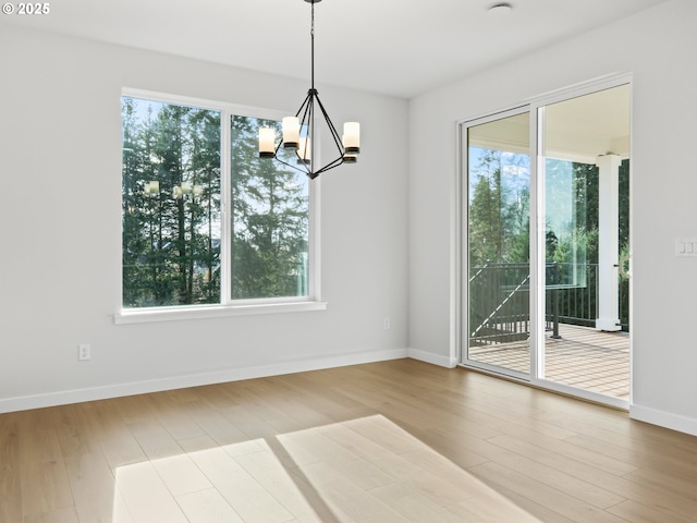 unfurnished dining area featuring a wealth of natural light, light hardwood / wood-style flooring, and a chandelier