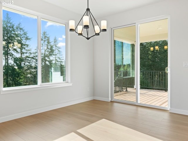 unfurnished dining area with an inviting chandelier and light hardwood / wood-style flooring