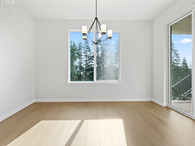 unfurnished dining area featuring a healthy amount of sunlight, a chandelier, and hardwood / wood-style flooring