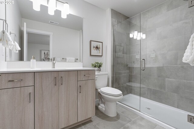 bathroom featuring a shower with door, toilet, vanity, and tile patterned flooring