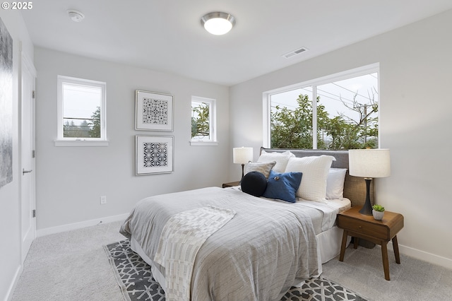 bedroom with light carpet and multiple windows