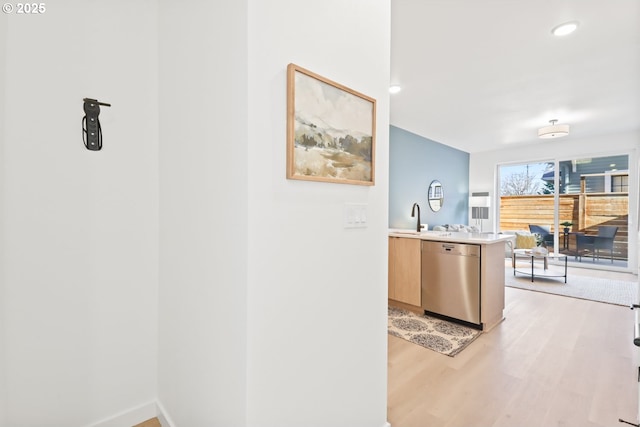 interior space featuring light brown cabinetry, sink, dishwasher, kitchen peninsula, and light hardwood / wood-style floors