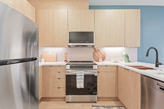 kitchen with light brown cabinetry, sink, decorative backsplash, and appliances with stainless steel finishes