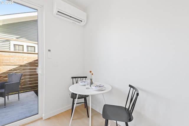 dining space featuring a wall unit AC and light wood-type flooring