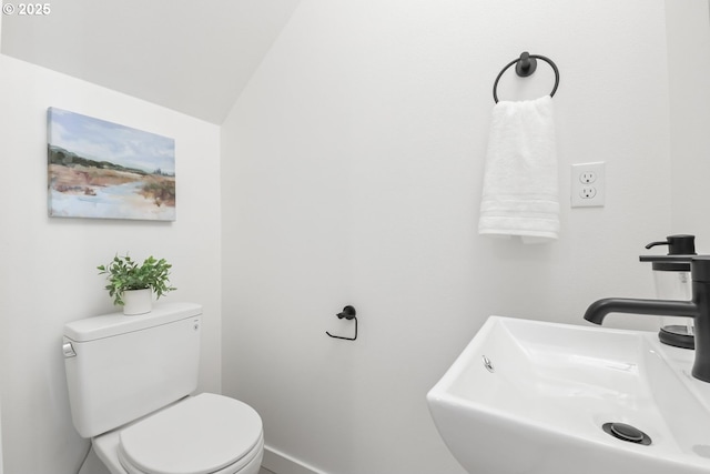 bathroom featuring lofted ceiling, sink, and toilet