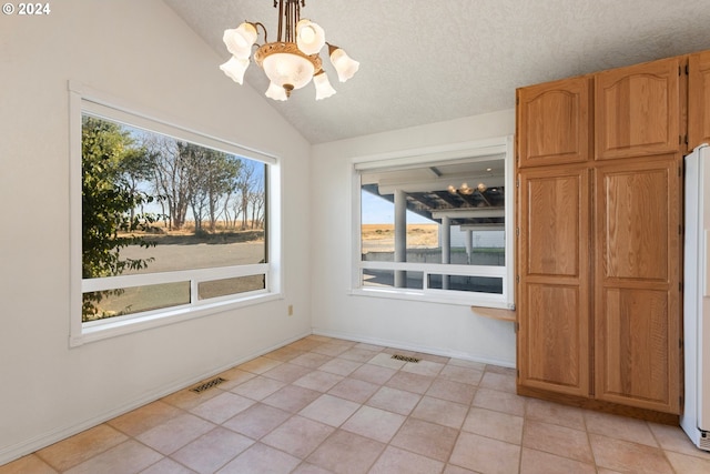 unfurnished dining area featuring a notable chandelier, a wealth of natural light, vaulted ceiling, and light tile patterned flooring