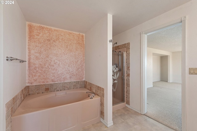 full bath with a bath, a textured ceiling, and a shower stall