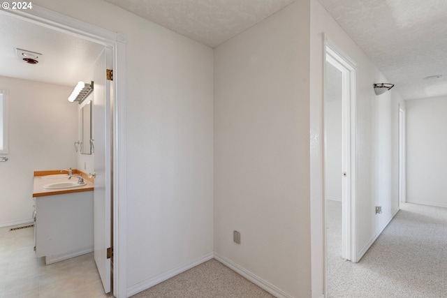 hall featuring a textured ceiling and sink