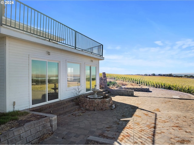 view of patio / terrace featuring a balcony and a rural view