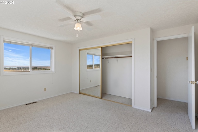 unfurnished bedroom featuring ceiling fan, a closet, light carpet, and multiple windows