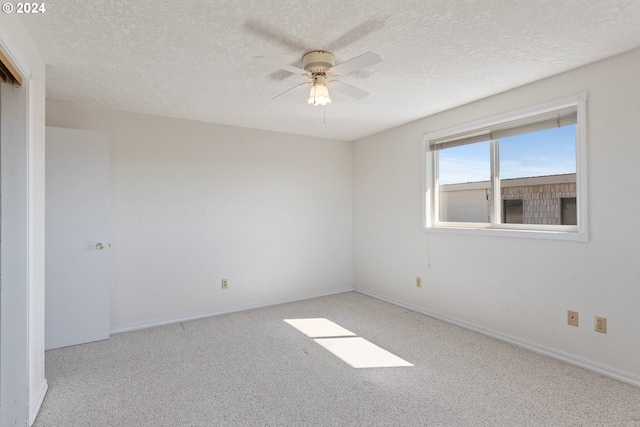 spare room featuring light carpet, ceiling fan, and a textured ceiling