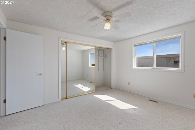 unfurnished bedroom with a textured ceiling, ceiling fan, light colored carpet, and a closet