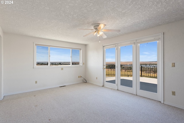 unfurnished room with a textured ceiling, carpet, and ceiling fan