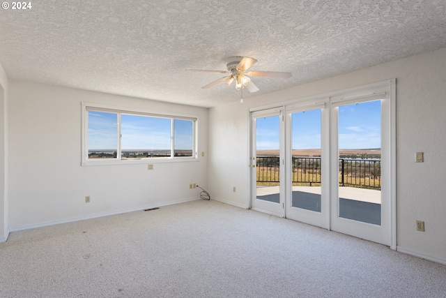 carpeted empty room featuring visible vents, a textured ceiling, baseboards, and ceiling fan