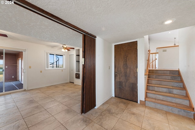 interior space featuring stairs, a textured ceiling, baseboards, and a ceiling fan