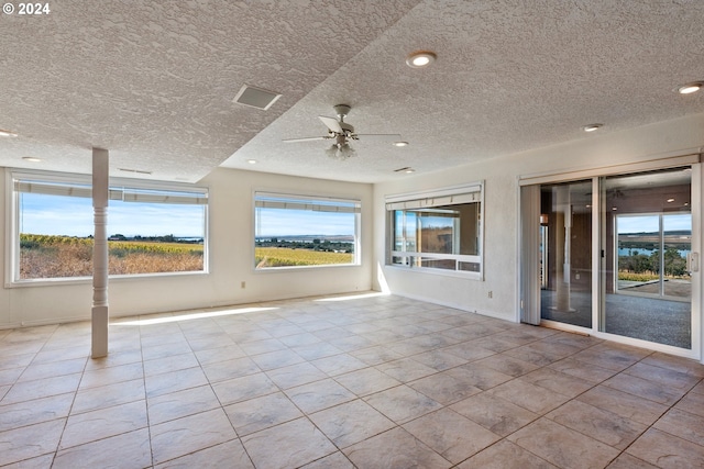 interior space featuring ceiling fan, a textured ceiling, light tile patterned floors, and a wealth of natural light