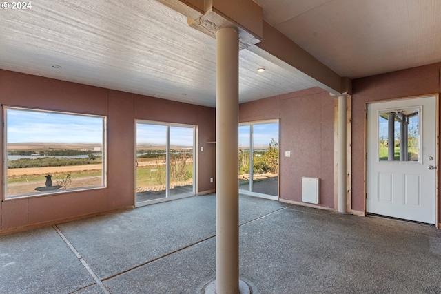 unfurnished sunroom featuring beam ceiling and ornate columns